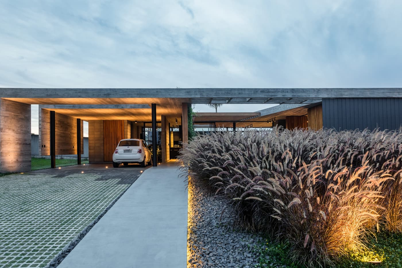 Ambiente da Casa Bloco em Criciúma com concreto aparente, madeira e grande abertura para o jardim