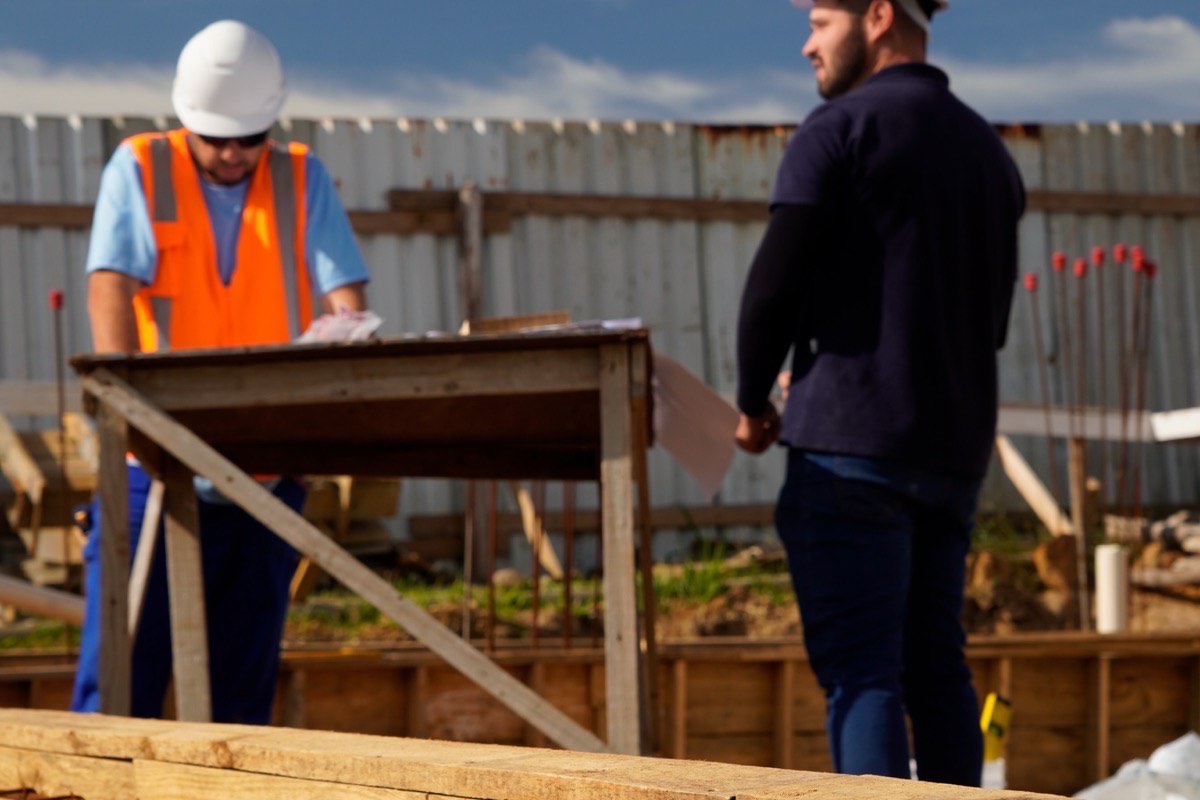 Engenheiro analisando planta e topografia de terreno para construção de casa de alto padrão em Criciúma